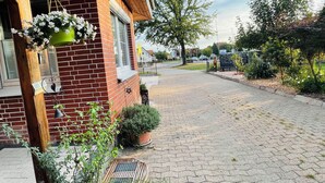En byggnad av tegel med hängande blomkorgar och en stenlagd gångväg som leder ut till en gata.