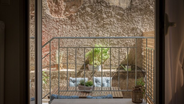 A balcony with a metal railing, potted plants, and a wooden bench. - Cozy Flat with Terrace & Patio near Lycabettus (Athens)
