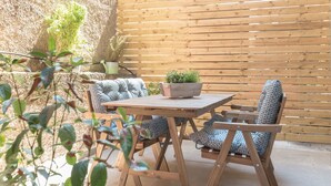 A wooden outdoor seating area with a table and chairs, a potted plant, and a wooden fence. - Cozy Flat with Terrace & Patio near Lycabettus (Athens)