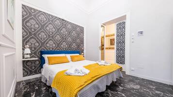 Une chambre à coucher bien rangée, avec un lit, une table de chevet et un mur décoré d’un motif.