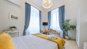 A hotel room with a large bed, a desk, a chair, a television, and a potted plant. - B&B Il Galleone (Messina)