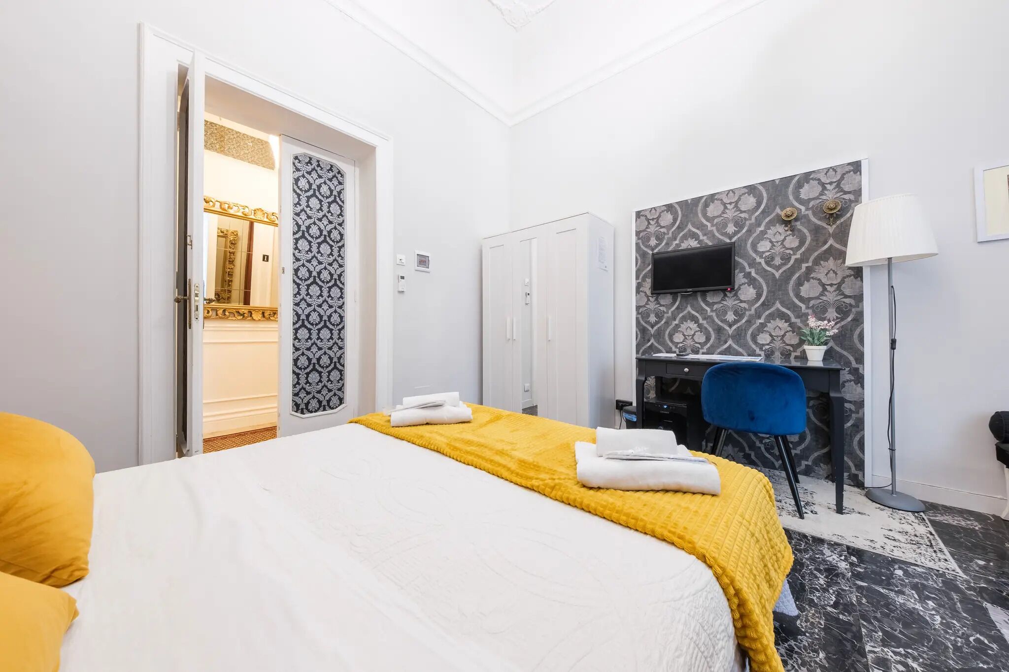 Une chambre d’hôtel avec un lit, un bureau, une chaise, une télévision et une lampe.