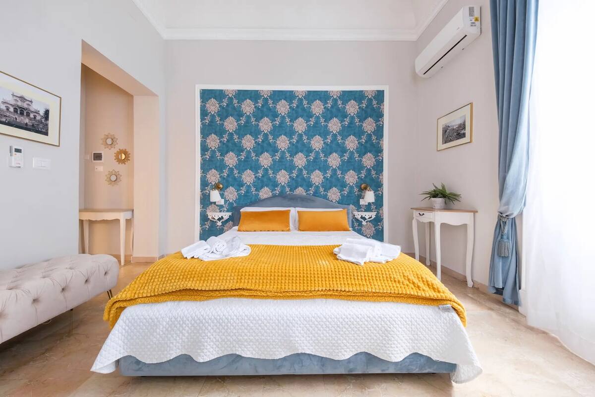 A neatly arranged bedroom with a bed, a bedside table, a chair, and a wall-mounted air conditioner.