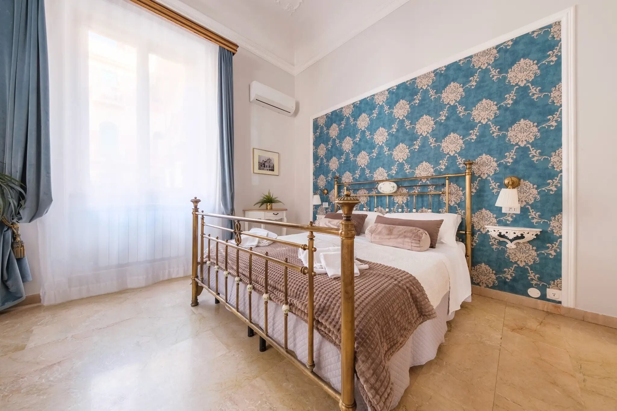 Una camera da letto con un letto, un comodino, una lampada e una finestra con tende.