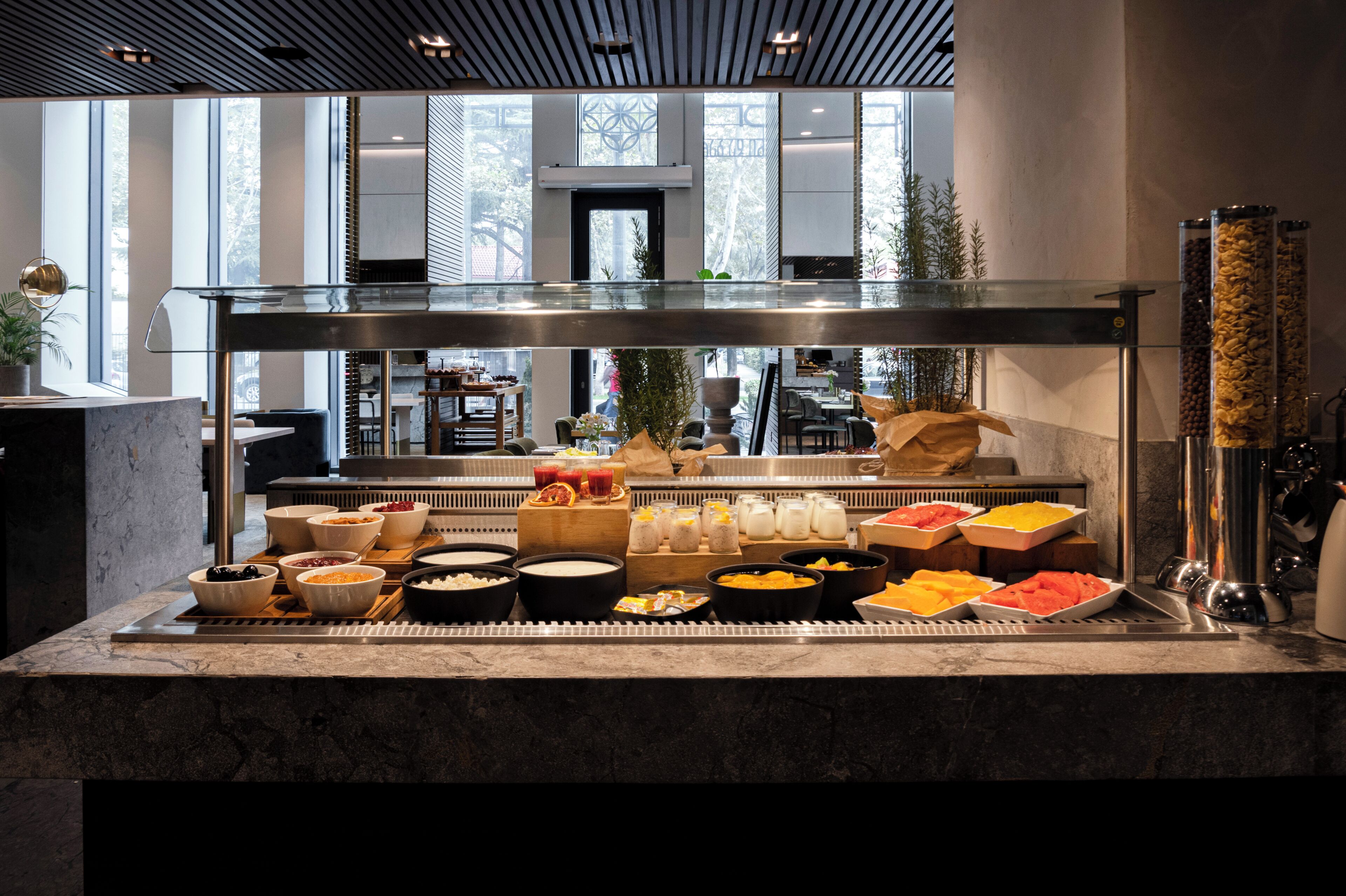 A buffet with various food items and a glass partition.