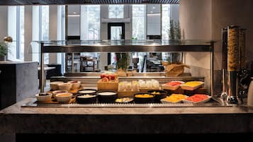 A buffet with various food items and a glass partition.