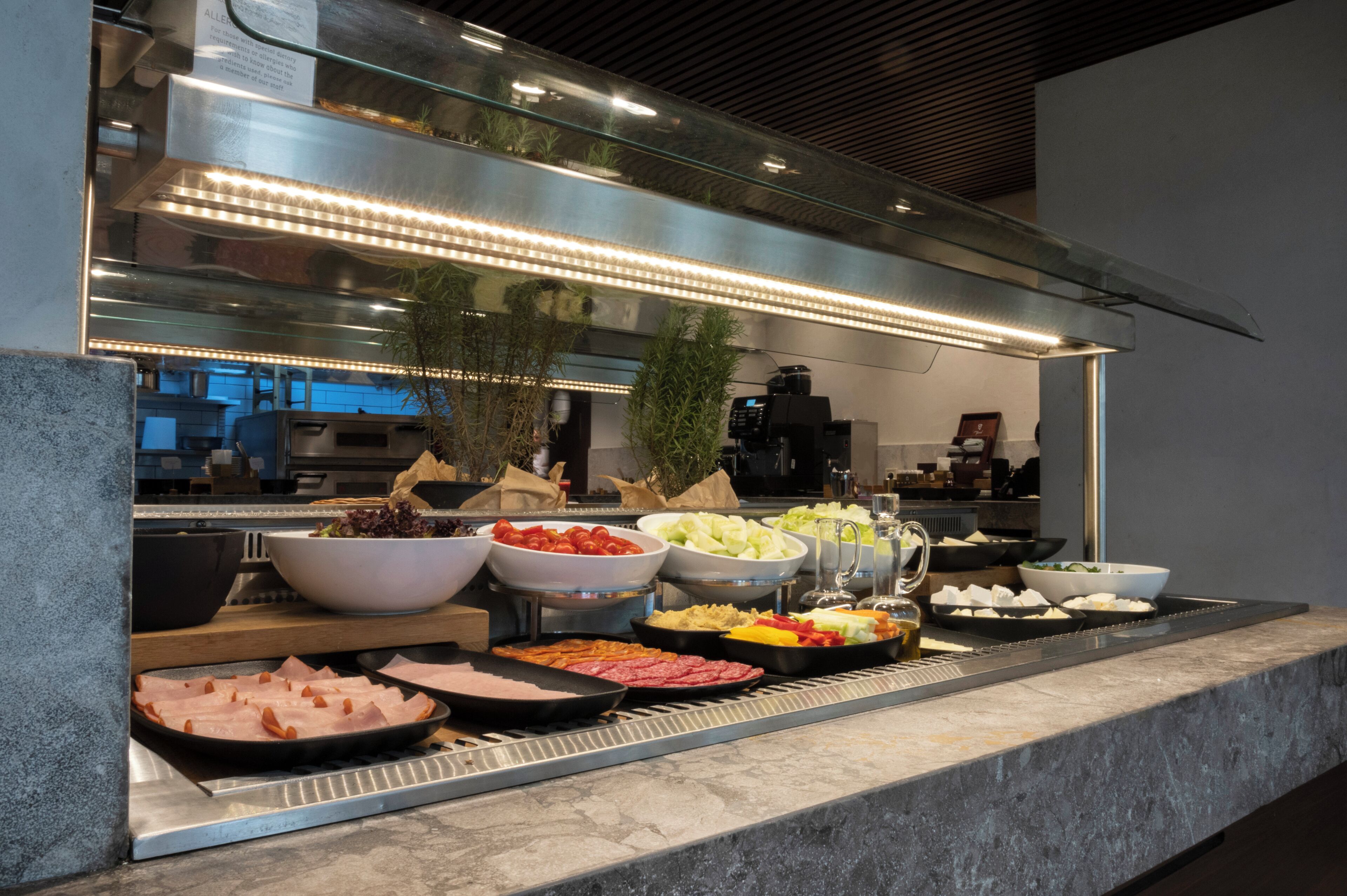 A buffet with various food items and a grill station.