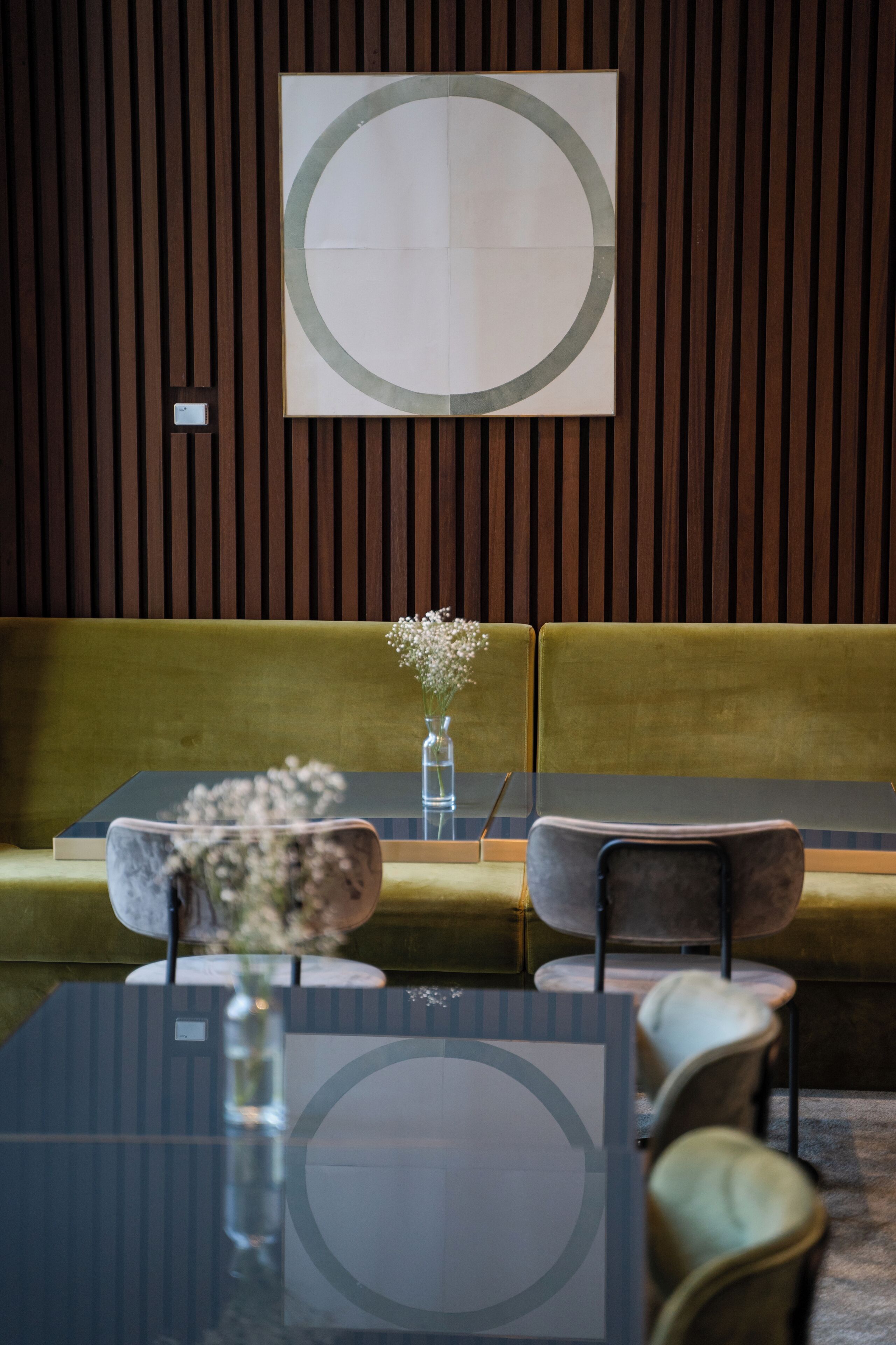 Un interior moderno con un sofá, una mesa de vidrio y una obra de arte minimalista en la pared.