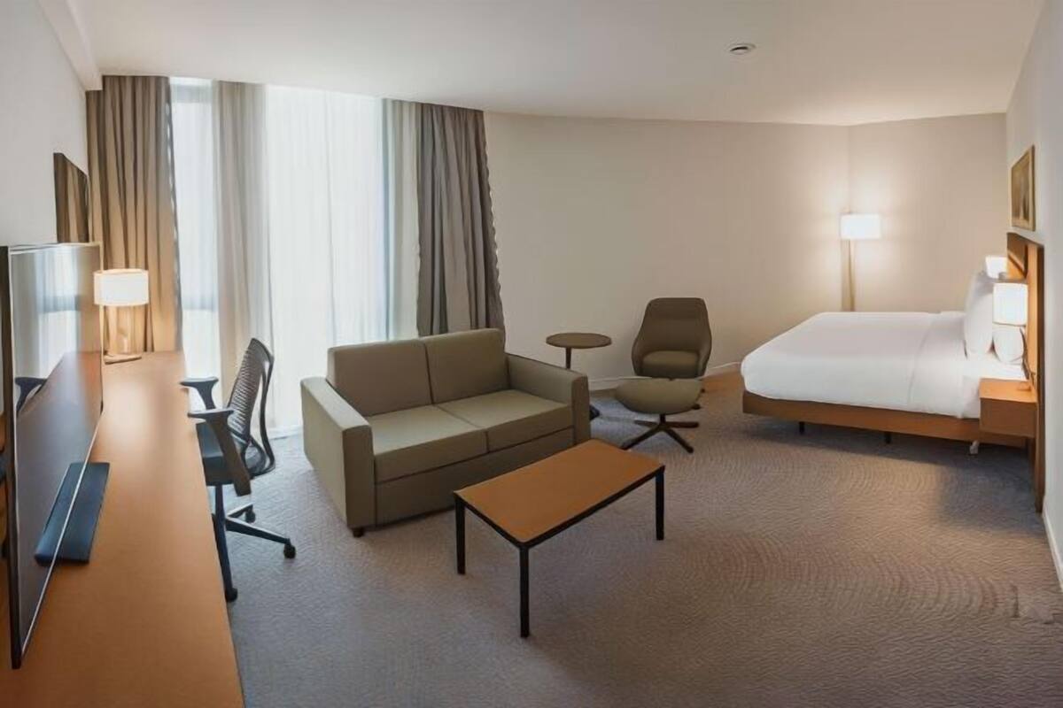 Een hotelkamer met een bed, een bank, een bijzettafeltje, een televisie en een lamp.