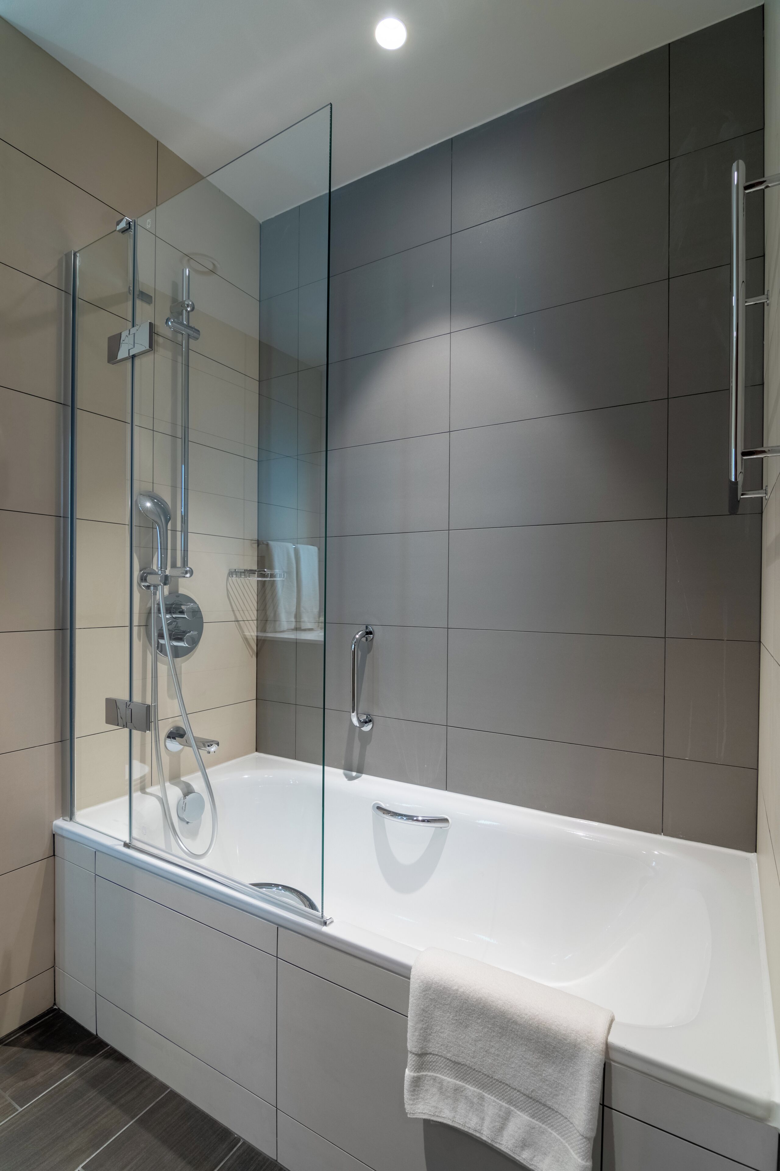 A modern bathroom with a glass-enclosed shower, a white bathtub, and a large mirror.
