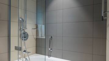 Un baño moderno con ducha de vidrio, una bañera blanca y un espejo grande.