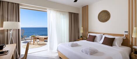 A hotel room with a large bed, a desk with a chair, a laptop, and slippers on the floor.