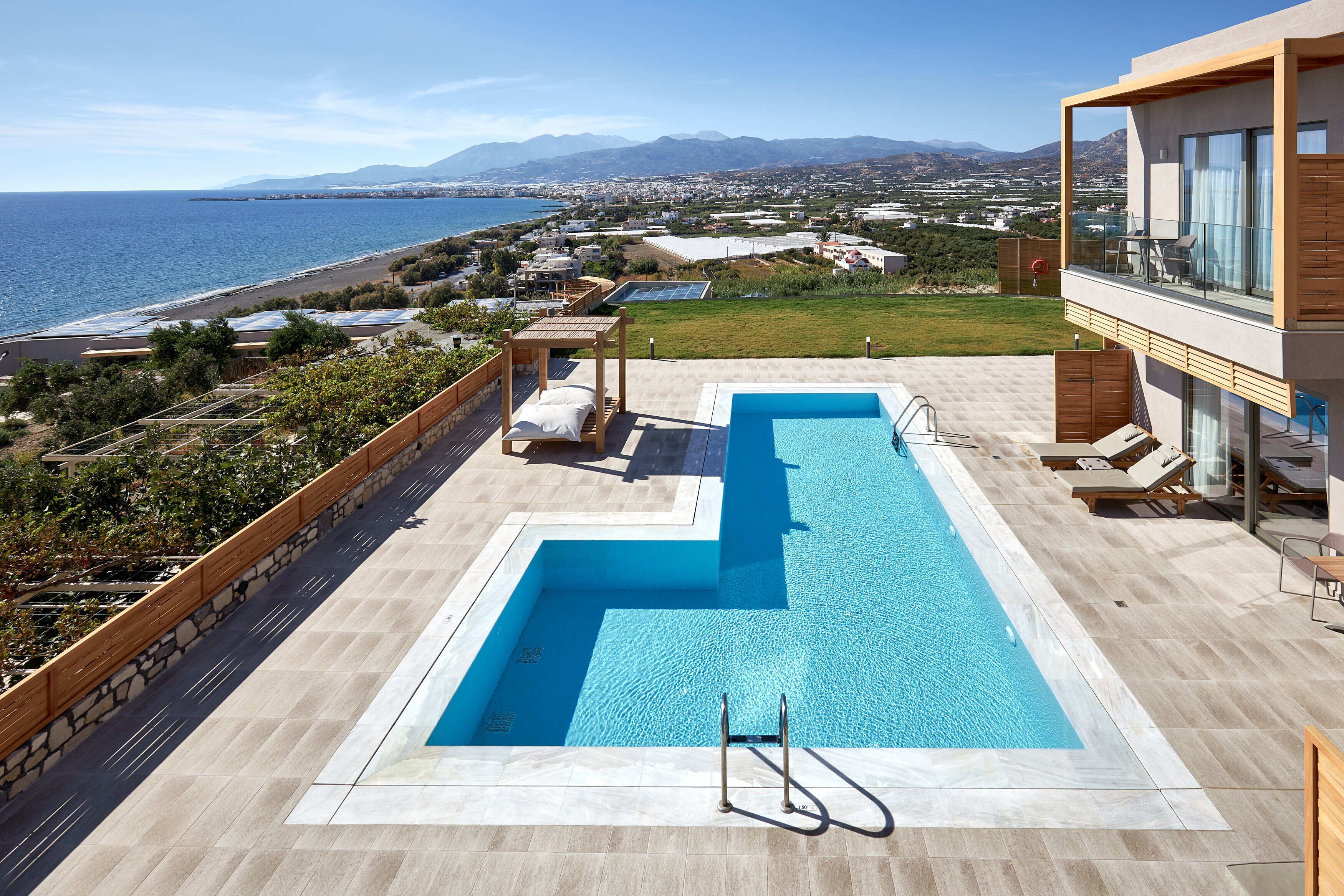 A rooftop pool with a clear view of the sea and mountains.