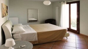 A bedroom with a bed, a chair, a table, a lamp, a mirror, and a window. - Girasole Apartment on 2 Levels - Renili House (pesaro)