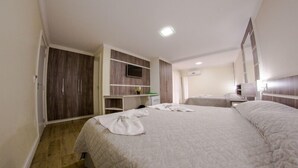 A hotel room with a large bed, a wardrobe, a desk, and a television.