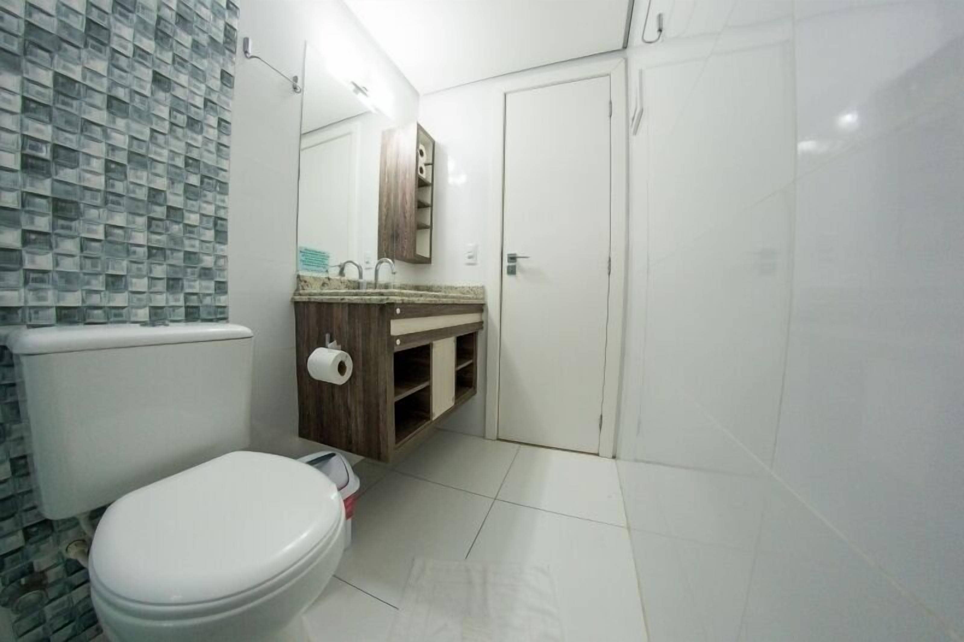 Un baño con inodoro, lavamanos con espejo y zona de ducha.