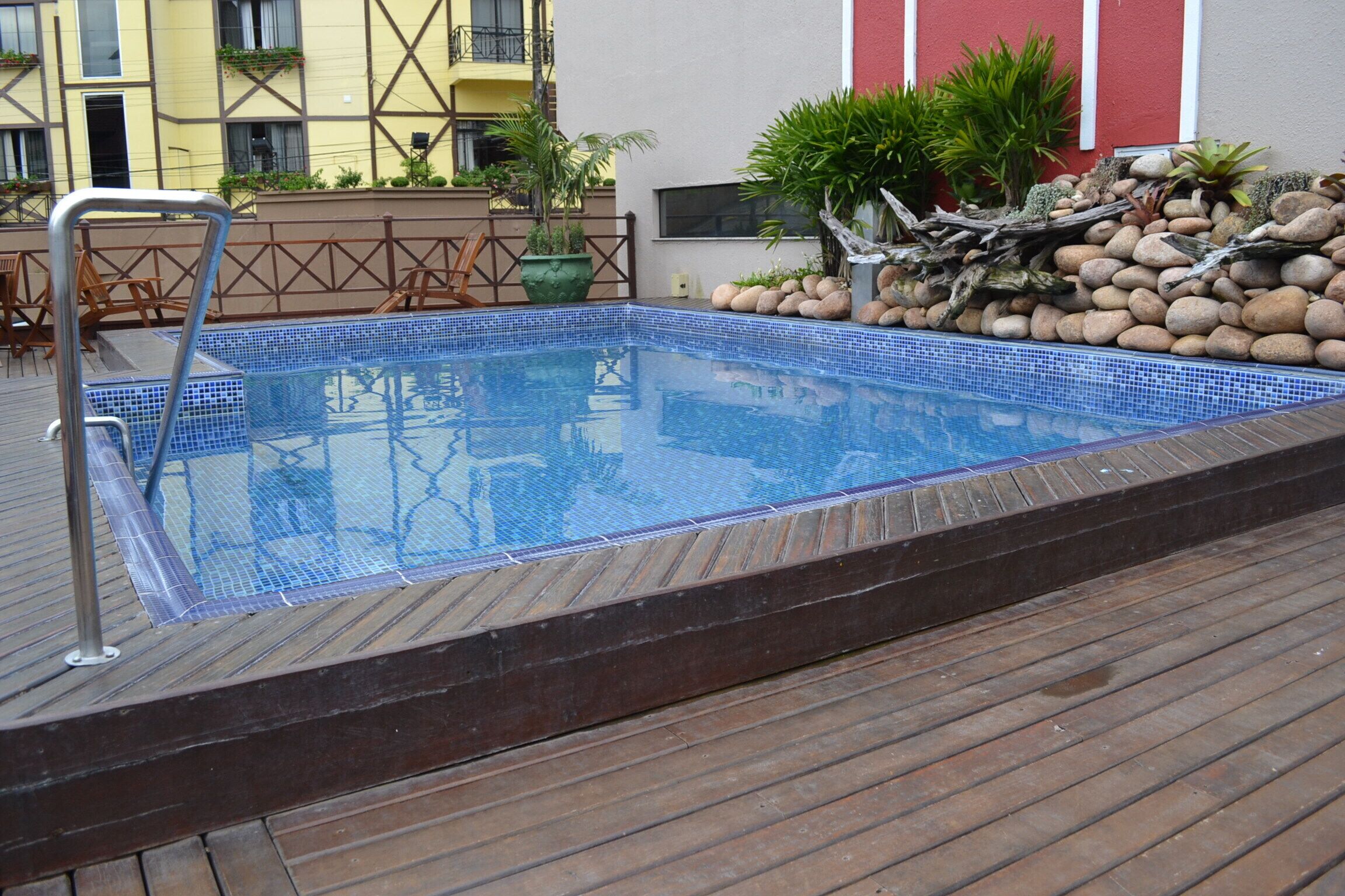 Una piscina con cubierta de madera, rodeada de plantas y rocas.