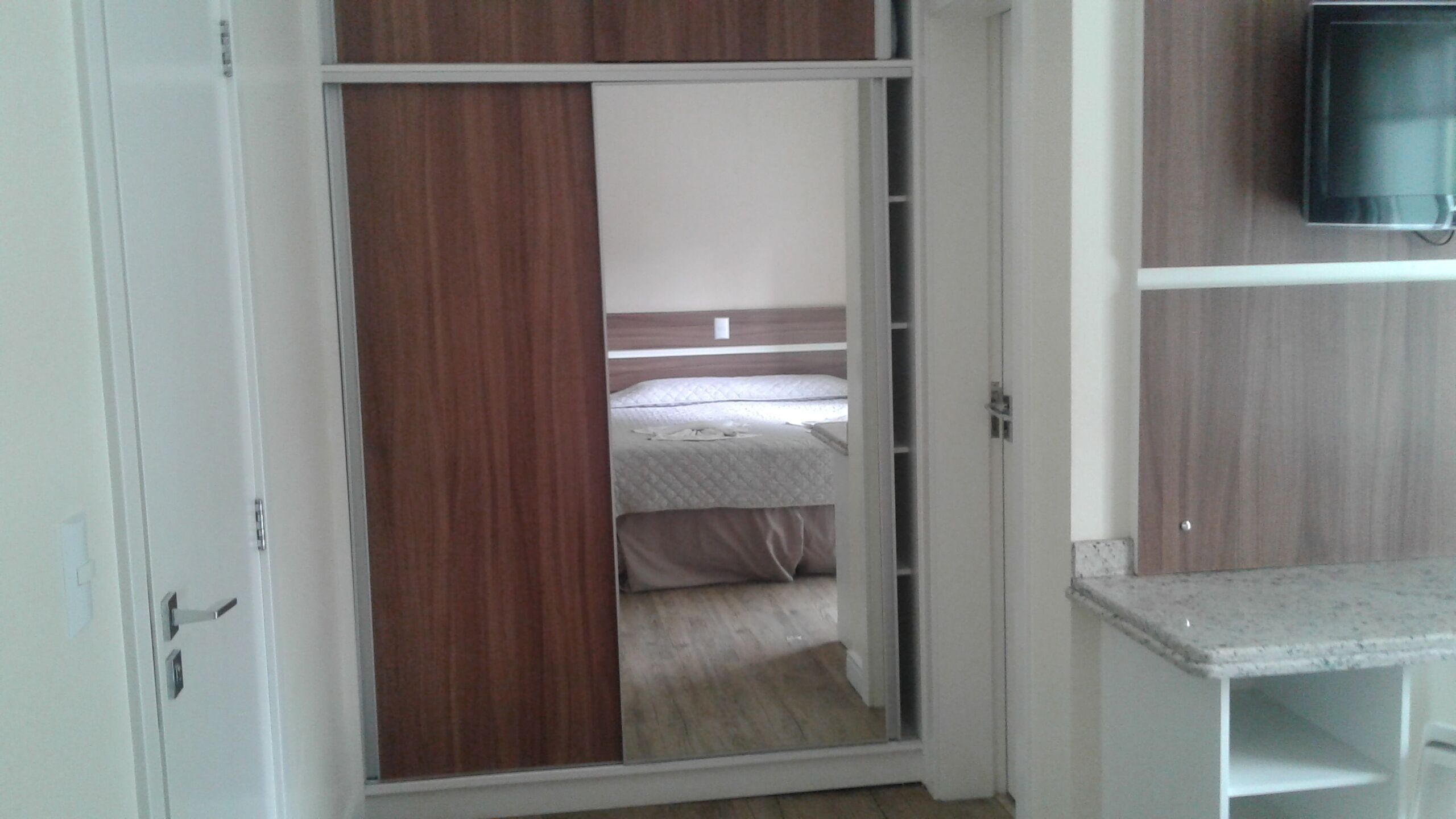 Un dormitorio con una cama, un armario y un televisor.