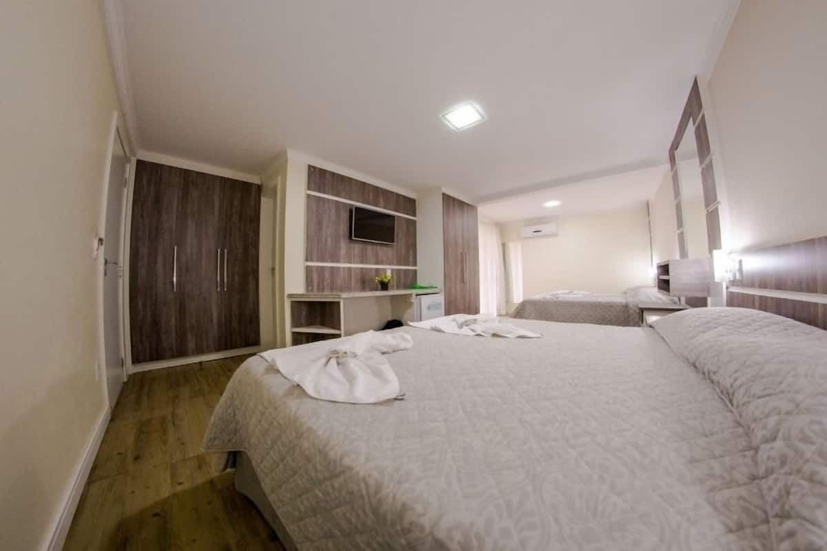 A hotel room with a large bed, a wardrobe, a desk, and a television.
