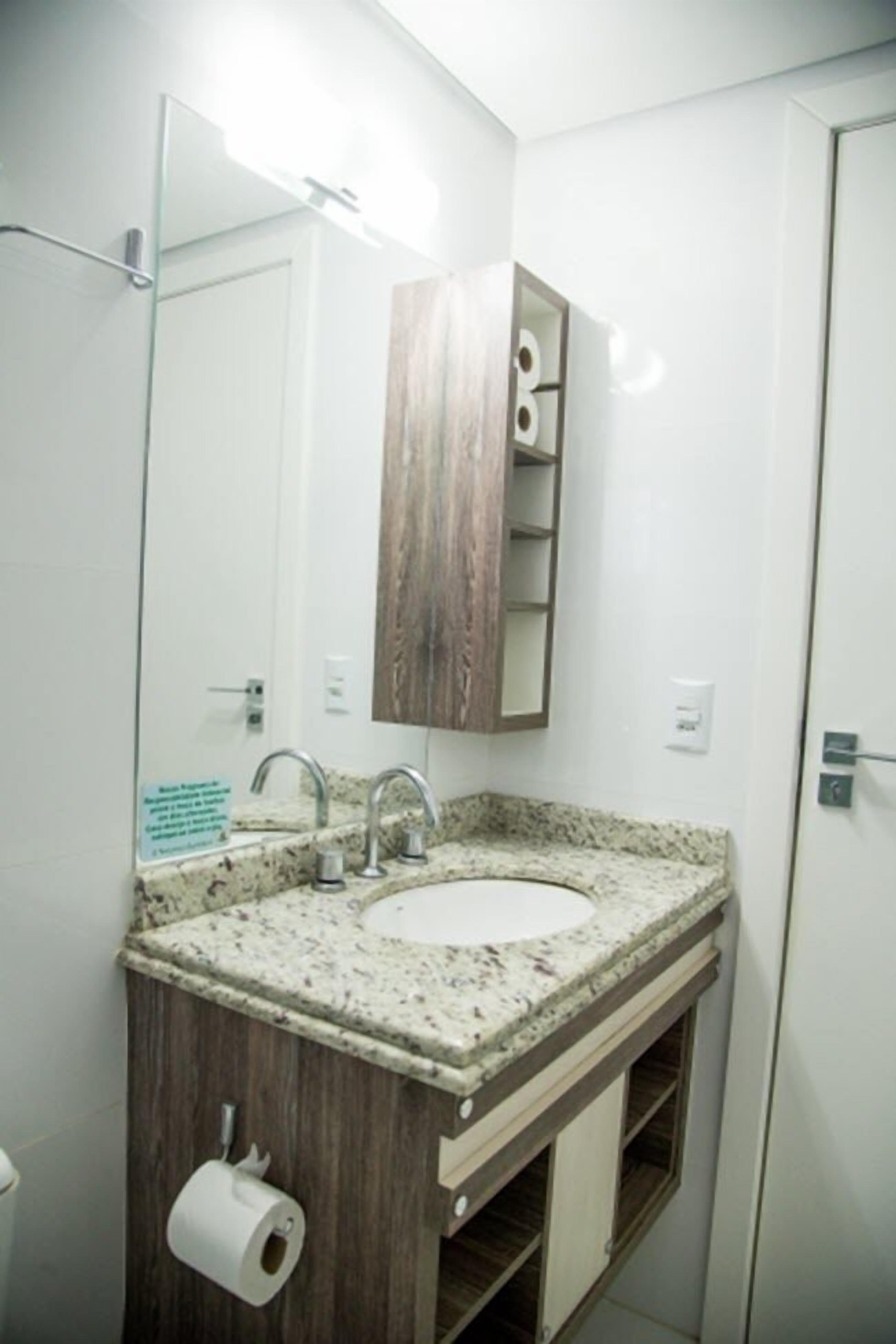 A bathroom with a granite countertop sink, a wooden vanity, and a mirror above the sink.