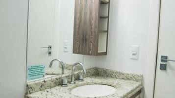 A bathroom with a granite countertop sink, a wooden vanity, and a mirror above the sink.