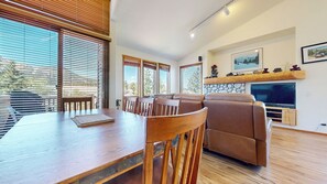 A modern living room with a dining table, wooden chairs, a sofa, and a fireplace. - Pet-Friendly & Stunning Mountain Views, Private Washer/Dryer & 1 Car Garage (Mammoth Lakes)