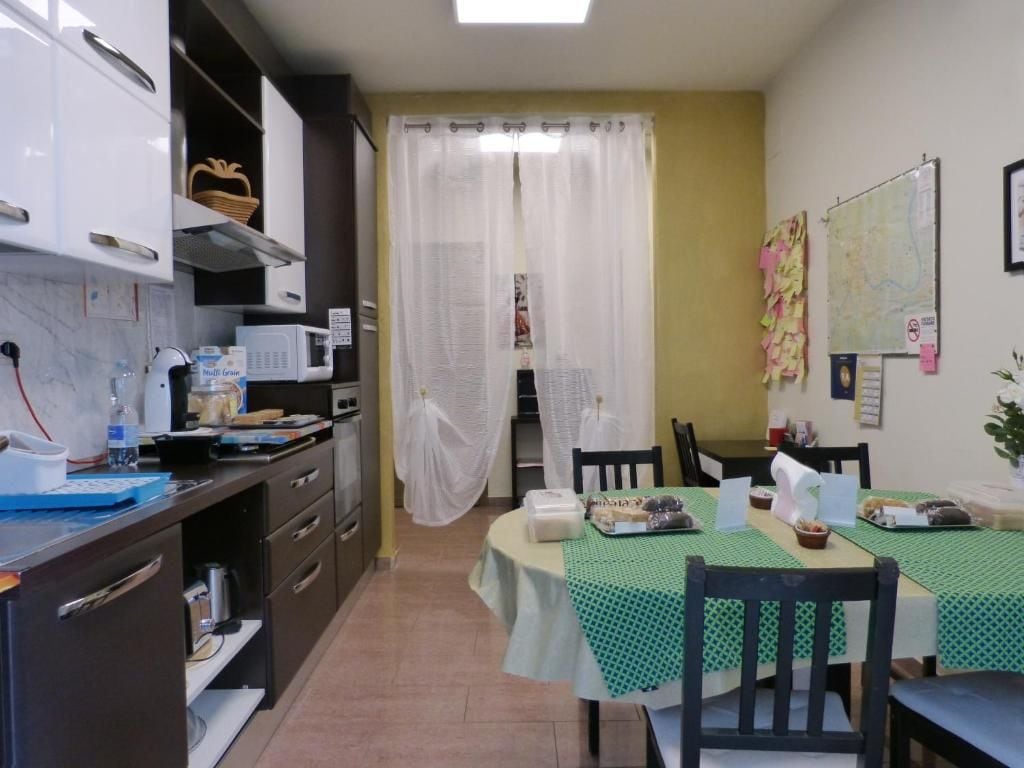 Cozinha compacta com área de refeições, incluindo micro-ondas, pia e mesa posta para dois.