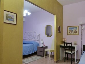Un dormitorio con cama, mesita de noche, silla, escritorio, lámpara y decoración en la pared.
