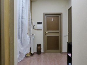 A hallway with a door marked '2', a radiator, a vase, and a white curtain. - Airport Pisa Rooms (Pisa)