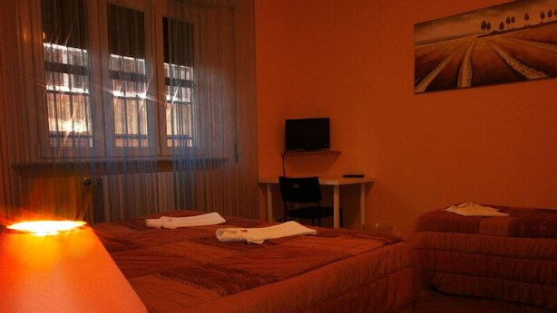 A hotel room with two beds, a TV on a small table, and a painting on the wall. - Airport Pisa Rooms (Pisa)