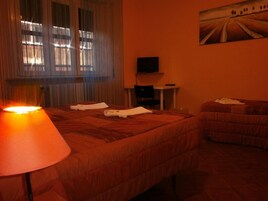 Una camera d'albergo con due letti, una televisione su un tavolino e un quadro appeso al muro.