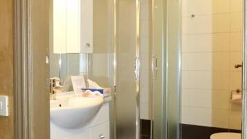 Un bagno con doccia vetrata, lavandino con specchio e WC.