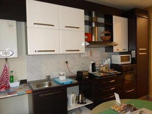 Una cocina compacta con armarios blancos, microondas, tostadora y hervidor.