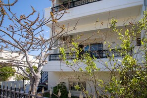 A multi-story building with balconies, a tree in the foreground, and a clear sky. - Dione Apartment with Terrace near Kalathas beach (Chania)