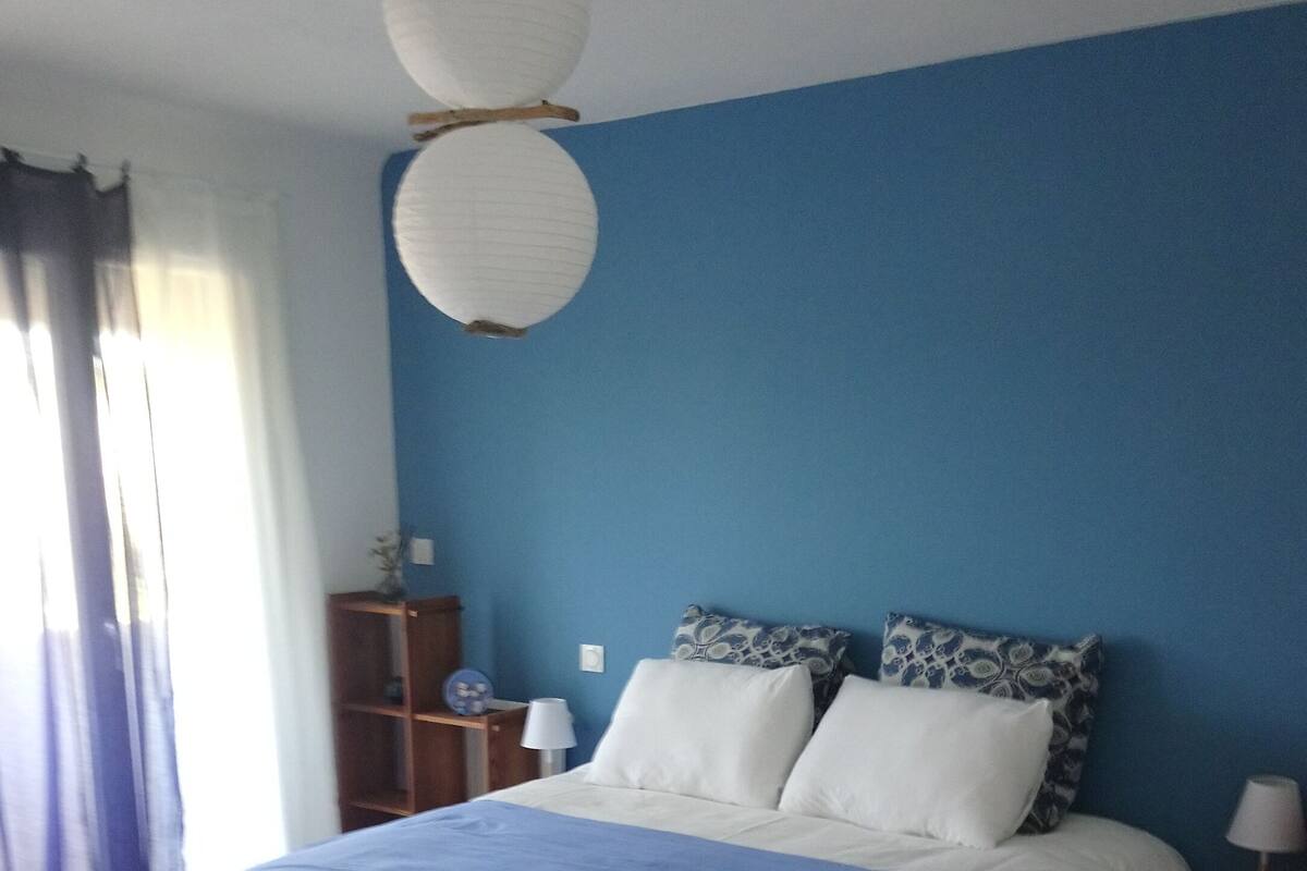 Un dormitorio con cama, mesita de noche, lámpara, luz de techo y alfombra estampada.