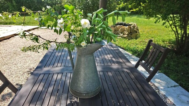 Une table de jardin ornée d’un vase contenant des fleurs blanches et des feuilles vertes.
