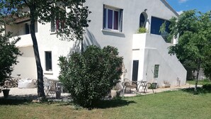Un immeuble de deux étages avec une façade blanche, de grandes fenêtres et un balcon.