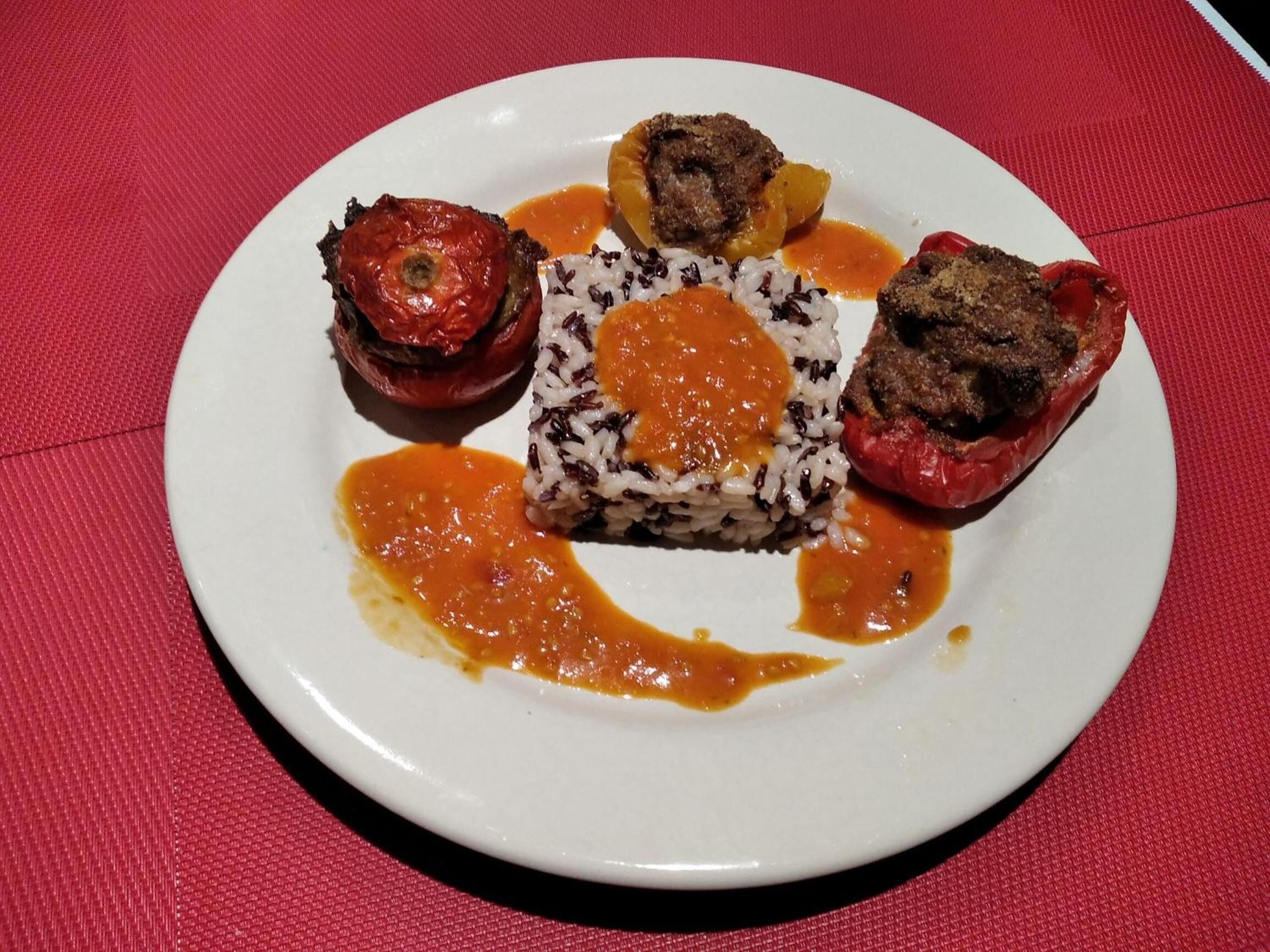 Un plato con pimientos rellenos, arroz y salsa.