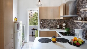 A modern kitchen with a central island, a built-in stove, and a tiled backsplash. - Dream City Apartment near Beach & Venetian Port (Chania)