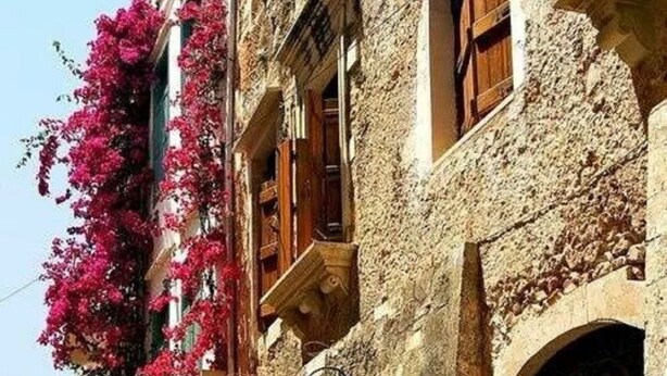 A narrow street lined with stone buildings, some with balconies adorned with pink flowers. - Dream City Apartment near Beach & Venetian Port (Chania)