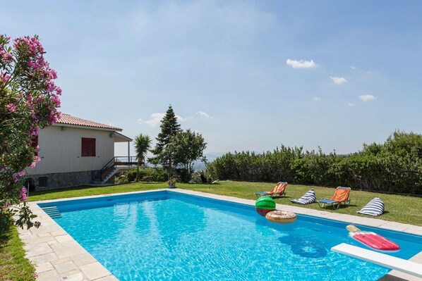 A swimming pool with lounge chairs and inflatable toys. - Dream Holidays in a Luxurious Garden Pool Villa (Pallini)