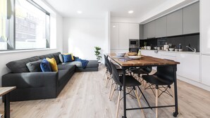 A modern kitchen with white cabinets, a wooden dining table, and black chairs. - Yugo Explore - Highfield Park (Dublin)