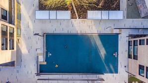 An aerial view of a modern building with a rooftop swimming pool, surrounded by other structures. - Yugo Explore - Highfield Park (Dublin)