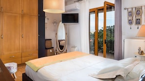 Ein Schlafzimmer mit einem Bett, einem Holzschrank, einem Fernseher, einem Spiegel und einem Balkon mit Blick.