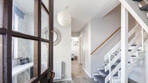 A hallway with a wooden door, a white radiator, and a staircase with white railings. - Fantastic Location with Stunning Estuary Views (Deganwy)