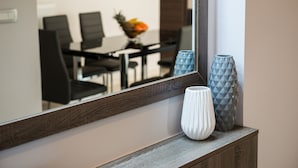 Un espace repas moderne avec une table et des chaises en bois, un panier de fruits et des vases décoratifs posés sur une console en bois.