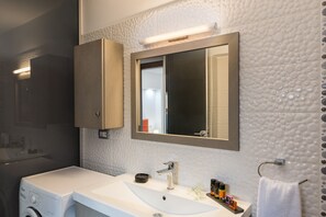 Ein modernes Badezimmer mit einem großen Waschbecken, einem Spiegel und einer Waschmaschine.