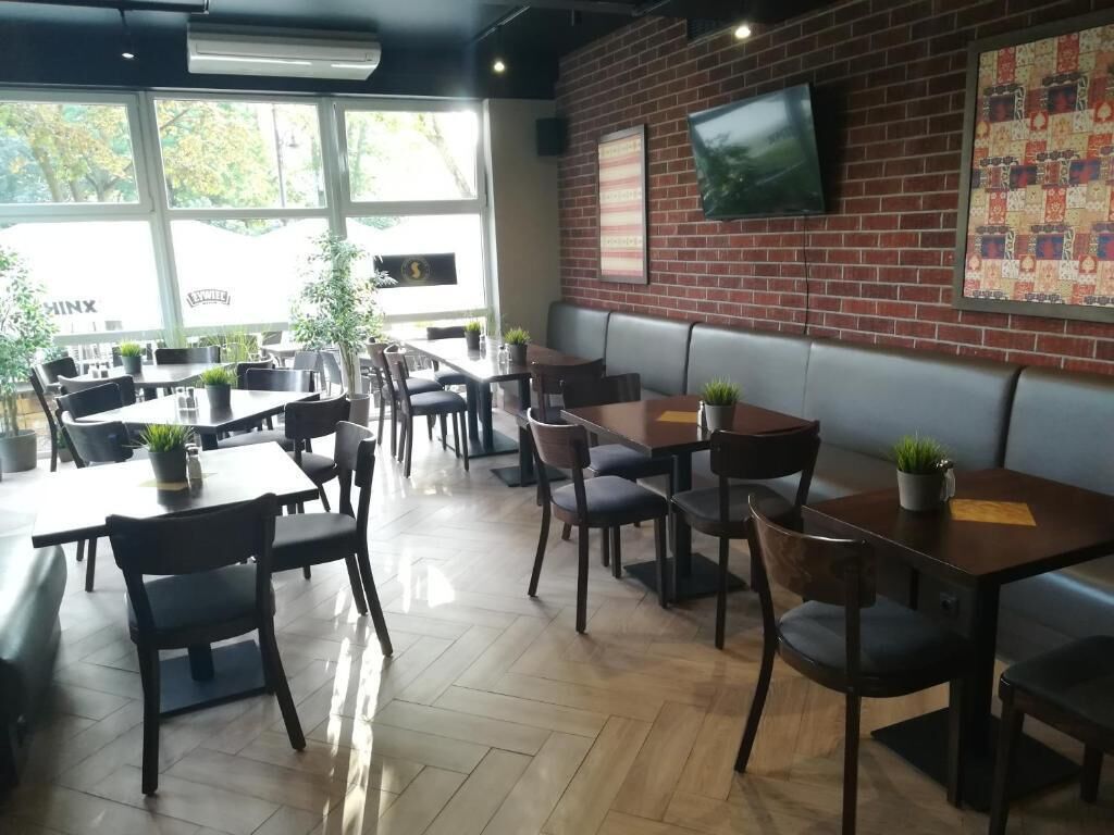 Un ristorante con posti a sedere a bancone e tavoli, ampie finestre e una parete in mattoni con un televisore.