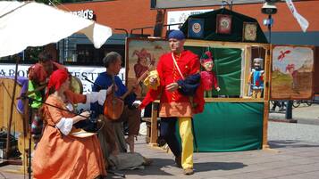 A street performance with a puppet show, a musician, and a performer in traditional attire.