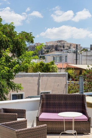 Une terrasse sur le toit, aménagée avec des meubles en osier, une table ronde et offrant une vue sur un paysage urbain historique.